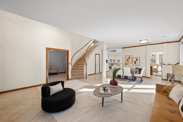 living room with light tile patterned floors, baseboards, decorative columns, and stairway