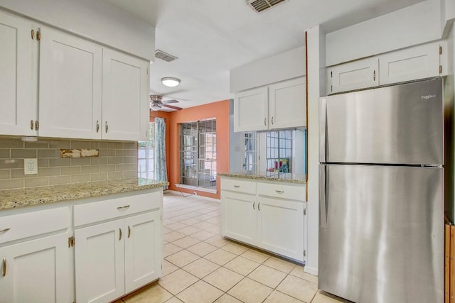 12333 Blue Water Dr, Austin, TX 78758 - kitchen with freestanding refrigerator, white cabinetry, and light tile patterned floors