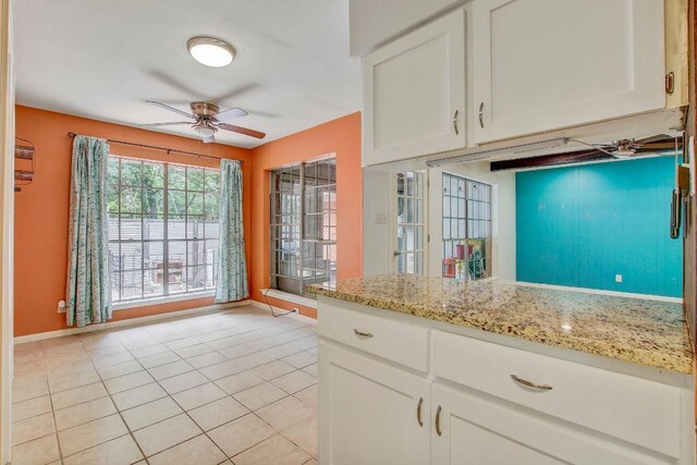 12333 Blue Water Dr, Austin, TX 78758 - kitchen featuring a ceiling fan, white cabinetry, baseboards, light tile patterned flooring, and light stone countertops