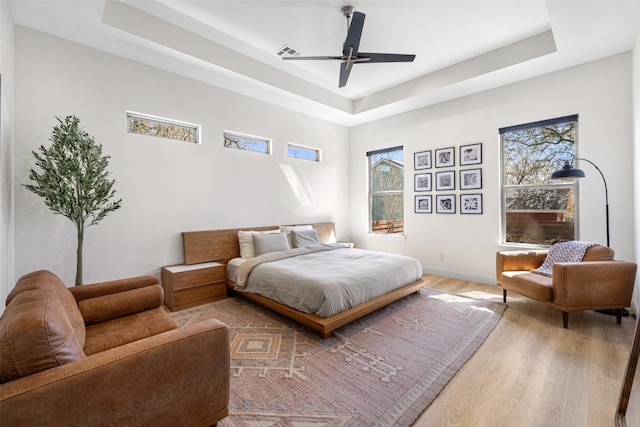 1017 S Quinlan Park Rd, Austin, TX 78732 - bedroom with a raised ceiling, light wood-style flooring, multiple windows, and ceiling fan