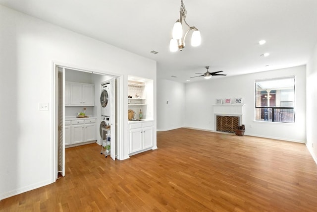611 E 45th St Unit 15, Austin, TX 78751 - unfurnished living room with stacked washer / drying machine, light wood-style flooring, ceiling fan, a fireplace, and recessed lighting