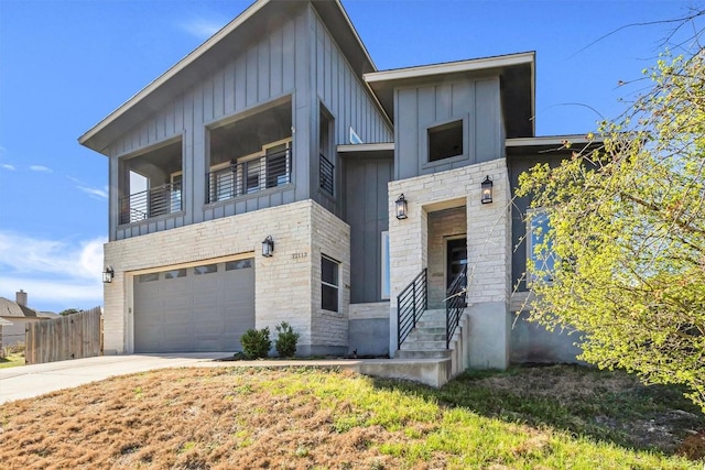 22113 Shotts Dr, Spicewood, TX 78669 - contemporary home featuring board and batten siding, an attached garage, concrete driveway, a balcony, and stone siding