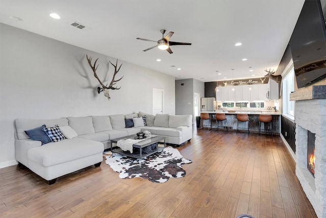 22113 Shotts Dr, Spicewood, TX 78669 - living room with a ceiling fan, dark wood-style flooring, a stone fireplace, and recessed lighting