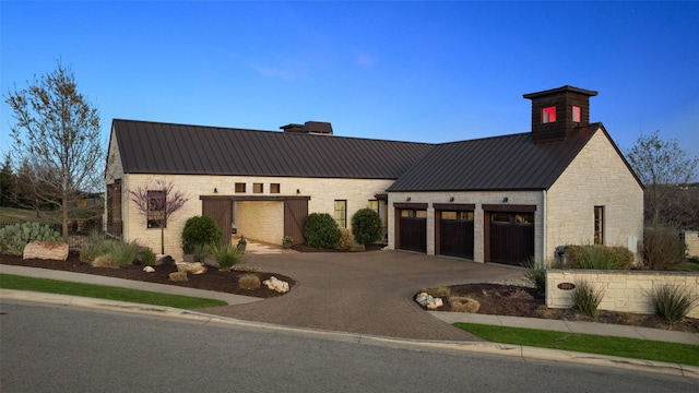 599 Vendemmia Bnd, Austin, TX 78738 - view of front facade with asphalt driveway, stone siding, a metal roof, a garage, and a standing seam roof