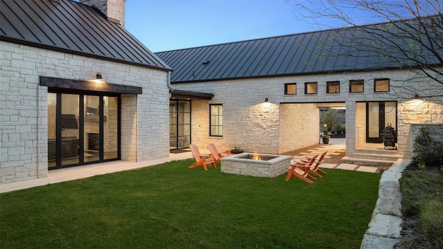 599 Vendemmia Bnd, Austin, TX 78738 - rear view of house with a standing seam roof, a metal roof, an outdoor fire pit, a lawn, and a chimney