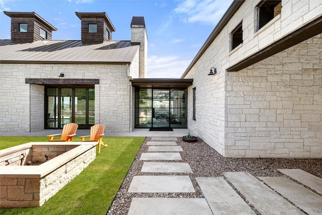 599 Vendemmia Bnd, Austin, TX 78738 - view of exterior entry featuring a standing seam roof, a chimney, and a metal roof
