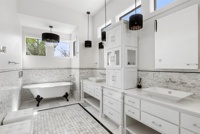 599 Vendemmia Bnd, Austin, TX 78738 - bathroom with vanity, a chandelier, a freestanding tub, tile walls, and a wainscoted wall