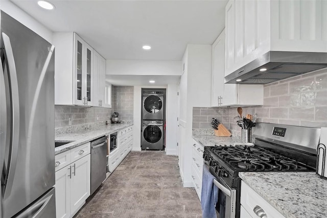 2001 Iroquois Ln, Austin, TX 78741 - kitchen with appliances with stainless steel finishes, stacked washer / drying machine, exhaust hood, backsplash, and white cabinets