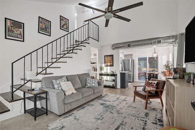 living room with a towering ceiling, visible vents, concrete floors, and stairway
