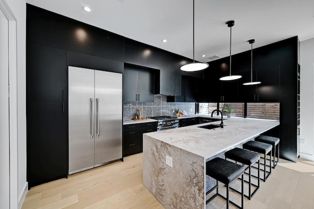 2109 Glendale Pl, Austin, TX 78704 - kitchen featuring premium appliances, dark cabinetry, a sink, pendant lighting, and light wood-style floors