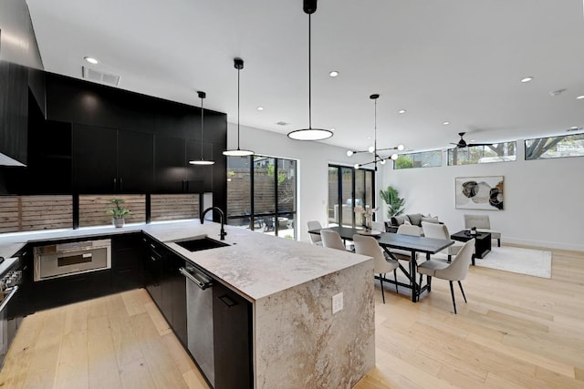 2109 Glendale Pl, Austin, TX 78704 - kitchen featuring dark cabinets, a sink, light wood-style flooring, appliances with stainless steel finishes, and modern cabinets