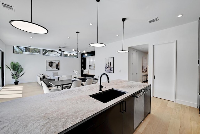 2109 Glendale Pl, Austin, TX 78704 - kitchen featuring a sink, light wood-style flooring, pendant lighting, light stone counters, and open floor plan