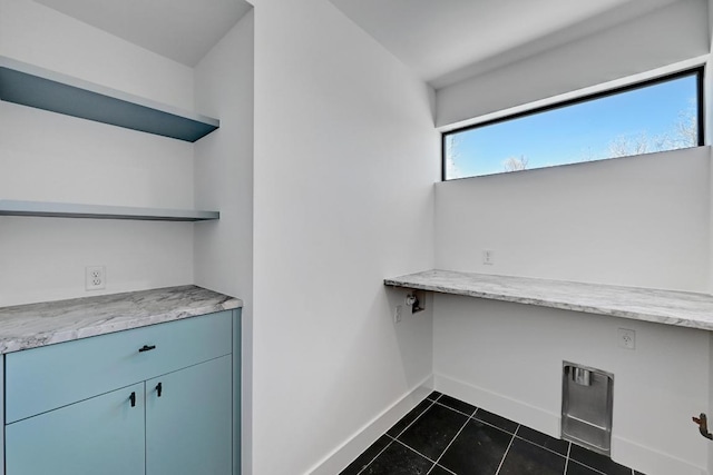 2109 Glendale Pl, Austin, TX 78704 - laundry room with baseboards, dark tile patterned flooring, and a desk
