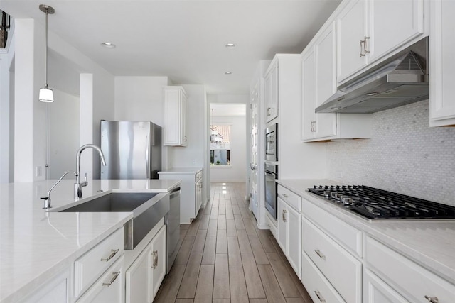 19604 Summit Glory Trl, Spicewood, TX 78669 - kitchen with stainless steel appliances, under cabinet range hood, white cabinets, tasteful backsplash, and hanging light fixtures