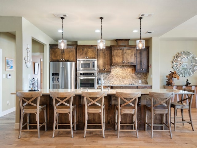 300 E Heron Dr, Marble Falls, TX 78654 - kitchen with stainless steel appliances, a spacious island, decorative backsplash, light countertops, and light wood-type flooring