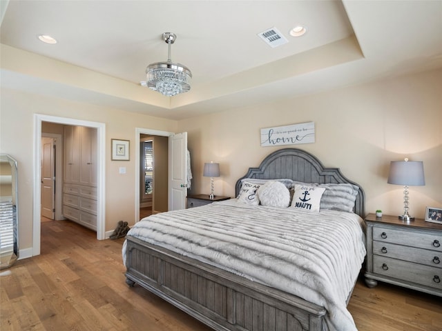 300 E Heron Dr, Marble Falls, TX 78654 - bedroom featuring a raised ceiling, wood finished floors, a chandelier, baseboards, and recessed lighting