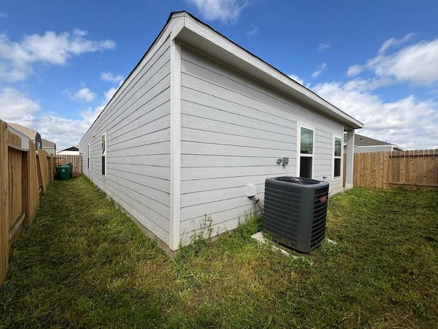 view of home's exterior with a fenced backyard, a lawn, and central AC