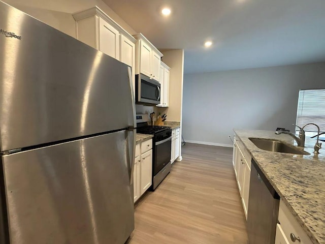 kitchen featuring a sink, white cabinetry, light wood finished floors, and stainless steel appliances