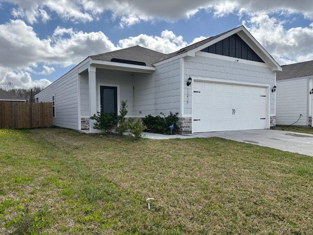 view of front of property featuring driveway, stone siding, fence, a front yard, and a garage