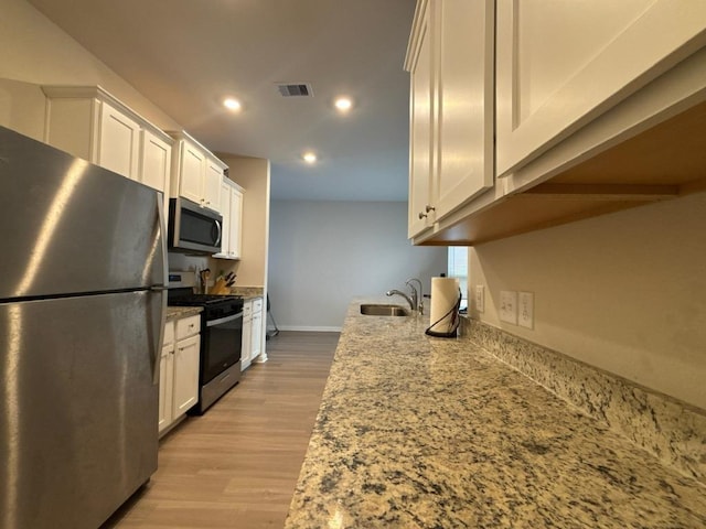 kitchen featuring visible vents, appliances with stainless steel finishes, white cabinetry, and a sink