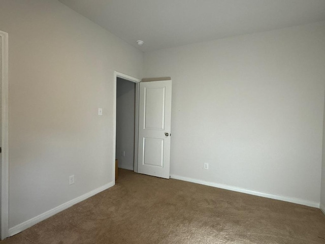 carpeted empty room featuring baseboards