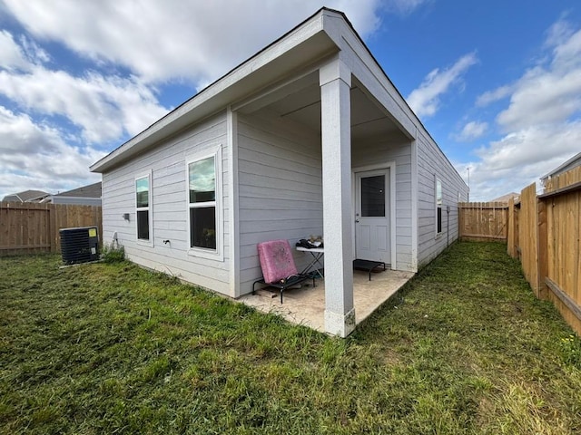rear view of house with a patio area, a fenced backyard, central AC unit, and a yard
