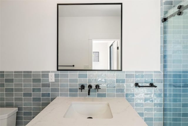 bathroom featuring toilet, tile walls, and vanity