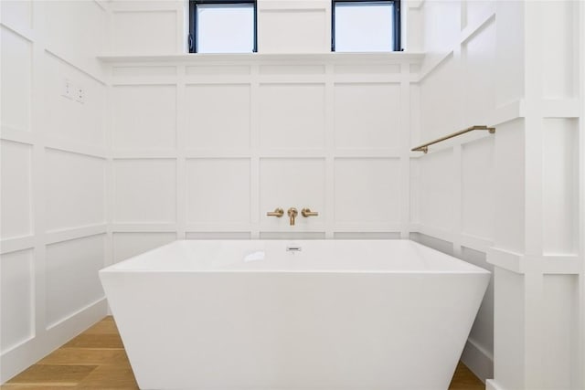 717 Meriden Ln, Austin, TX 78703 - bathroom featuring a decorative wall, a freestanding tub, and wood finished floors
