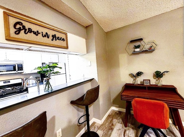 interior space featuring wood finished floors, baseboards, and a textured ceiling