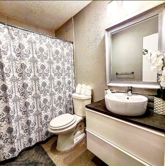 bathroom with vanity, a shower with curtain, a textured ceiling, toilet, and a textured wall
