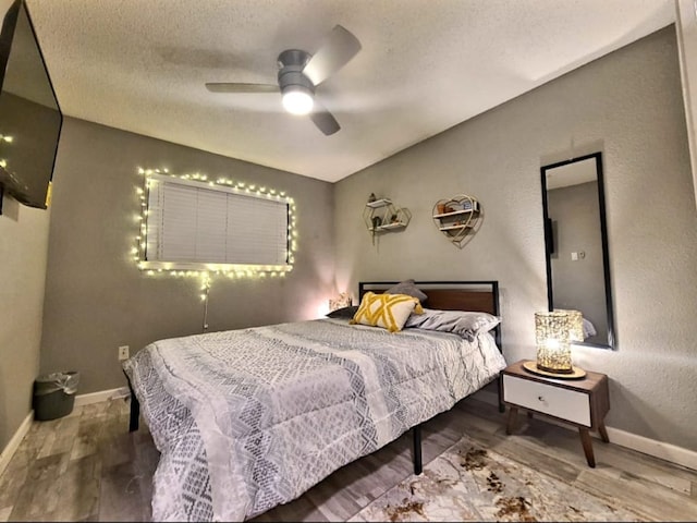 bedroom featuring a textured ceiling, lofted ceiling, baseboards, and wood finished floors