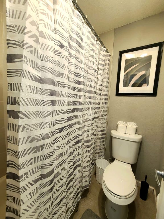 full bath featuring curtained shower, baseboards, and toilet