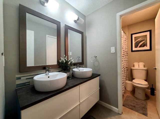 bathroom featuring double vanity, toilet, baseboards, and a sink