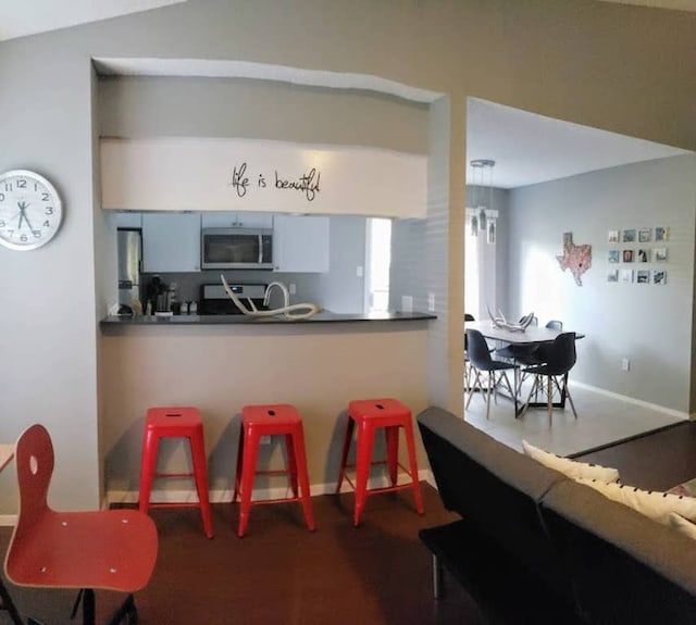 kitchen featuring stainless steel microwave, dark countertops, and baseboards