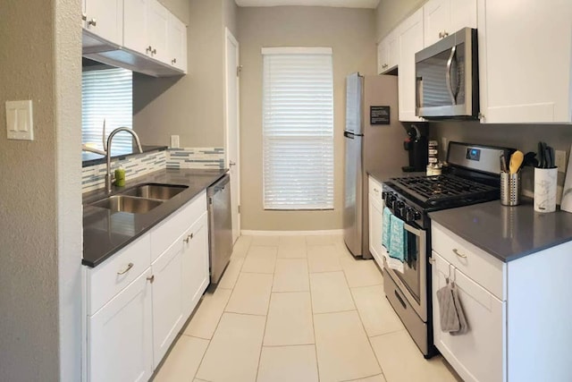kitchen featuring dark countertops, white cabinets, appliances with stainless steel finishes, and a sink
