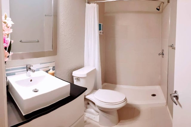full bathroom with vanity, toilet, a textured wall, and a stall shower