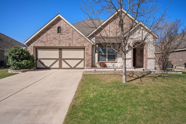 tudor home with concrete driveway, an attached garage, brick siding, and a front lawn