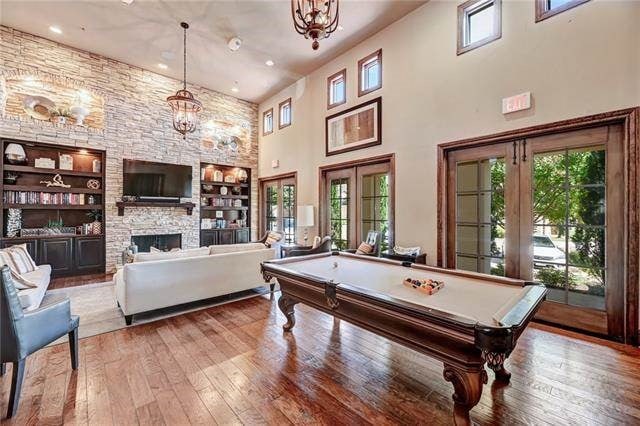 104 Bella Toscana Ave Unit 2301, Lakeway, TX 78734 - rec room featuring a towering ceiling, billiards, built in shelves, hardwood / wood-style floors, and a stone fireplace