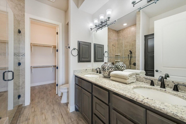 104 Bella Toscana Ave Unit 2301, Lakeway, TX 78734 - full bathroom with a stall shower, double vanity, toilet, a walk in closet, and wood finished floors