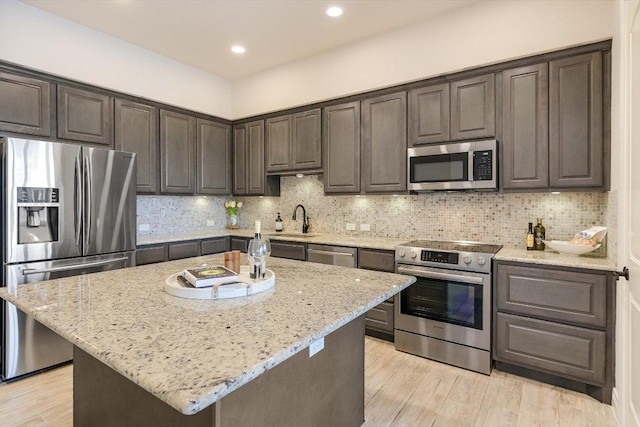 104 Bella Toscana Ave Unit 2301, Lakeway, TX 78734 - kitchen featuring stainless steel appliances, light wood-style flooring, light stone counters, dark brown cabinetry, and decorative backsplash