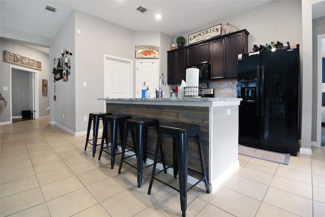 180 Sunshine Ln, Kyle, TX 78640 - kitchen featuring light tile patterned flooring, visible vents, a center island with sink, and black fridge with ice dispenser