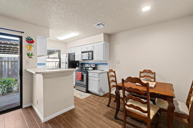9226 Jollyville Rd Unit 170, Austin, TX 78759 - kitchen with stainless steel appliances, light countertops, wood finished floors, a peninsula, and recessed lighting