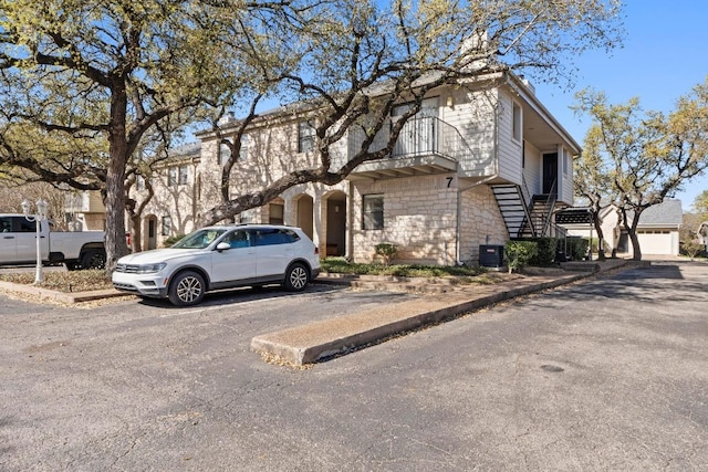 9226 Jollyville Rd Unit 170, Austin, TX 78759 - multi unit property with central AC unit, stairway, stone siding, and uncovered parking