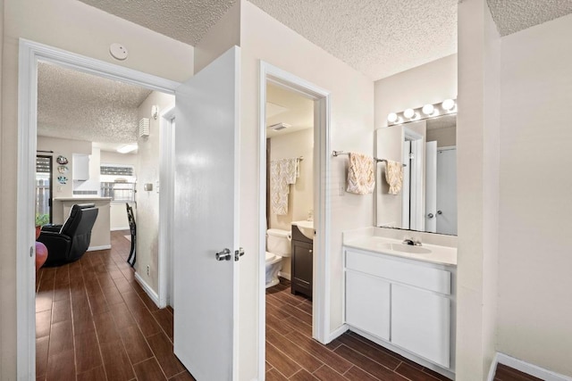 9226 Jollyville Rd Unit 170, Austin, TX 78759 - bathroom featuring a textured ceiling, wood finished floors, vanity, toilet, and baseboards