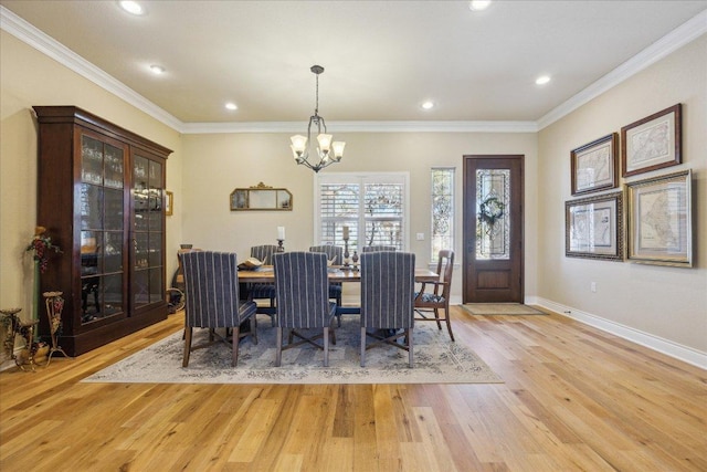dining room featuring light wood-type flooring, crown molding, an inviting chandelier, and baseboards