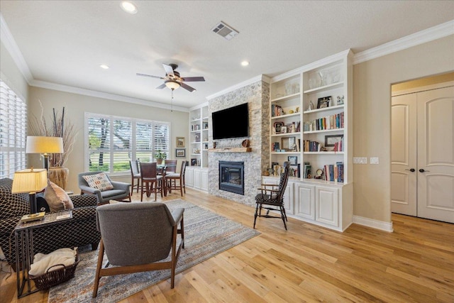 living area featuring crown molding, ceiling fan, a fireplace, and visible vents