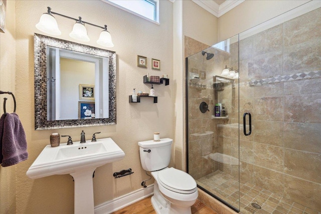 bathroom featuring baseboards, toilet, crown molding, wood finished floors, and a stall shower