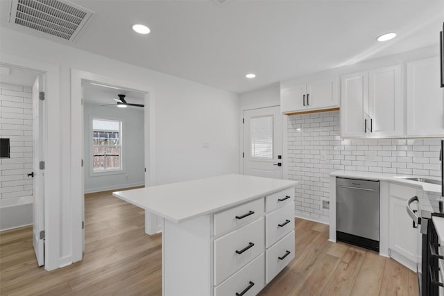 kitchen featuring visible vents, stainless steel dishwasher, light wood-style flooring, and light countertops
