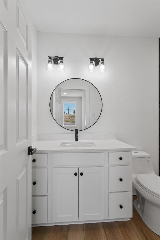 bathroom featuring toilet, vanity, and wood finished floors