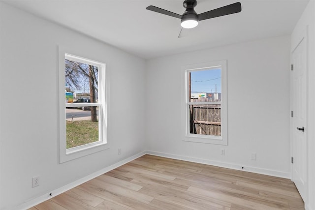 spare room with baseboards, a ceiling fan, and light wood-style floors